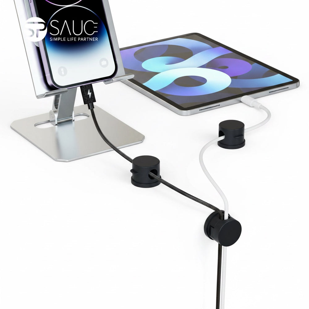 The Remote Desk magnetic cable clips in black holding charging cables on a white desk surface next to a tablet stand.